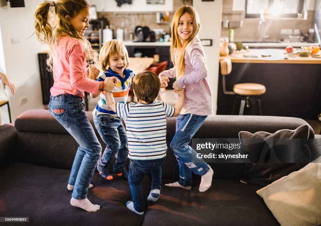 Small happy kids having fun while playing on sofa at home.
