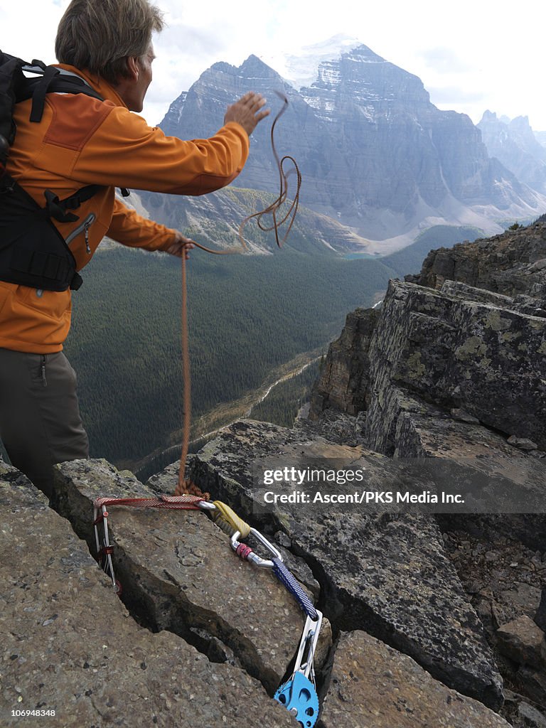 Climber throws rope from summit anchor