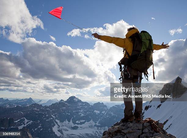 climber holds red flag on high mountain summit - media summit fotografías e imágenes de stock