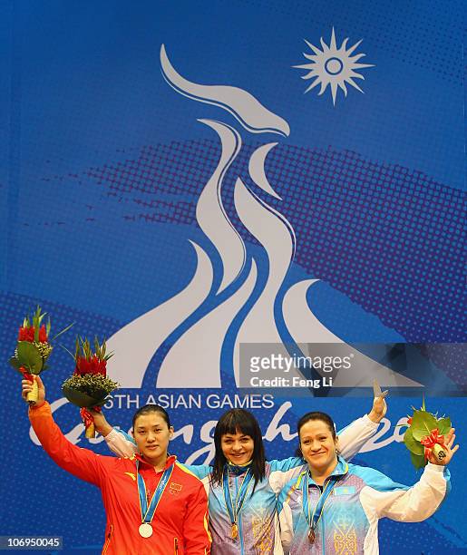 Silver medalist Cao Lei of China, gold medalist Svetlana Podobedova of Kazakhstan and bronze medalist Tatyana Khromova of Kazakhstan celebrates...