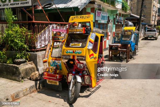 tricycles and car parked on the street in banaue, philippines - filipino tricycle stock pictures, royalty-free photos & images