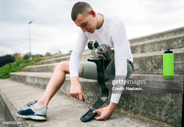 young runner adjusting prosthetic leg for running with screwdriver - prosthetic leg stock pictures, royalty-free photos & images