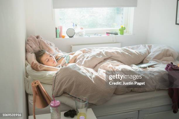 lazy teenage girl on smartphone in bed - messy bedroom stockfoto's en -beelden