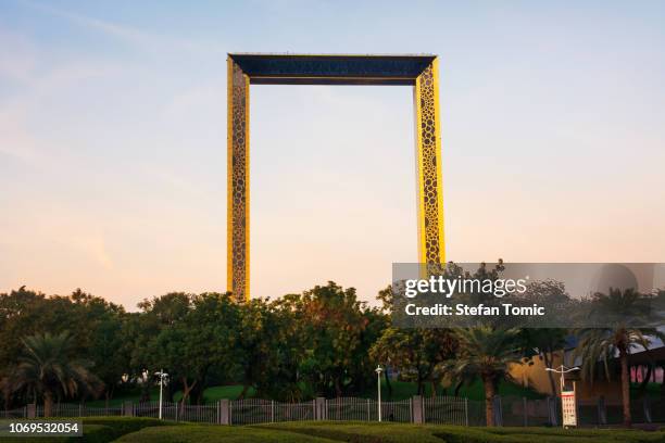 dubai frame gebouw met palmbomen bij zonsondergang - dubai frame stockfoto's en -beelden