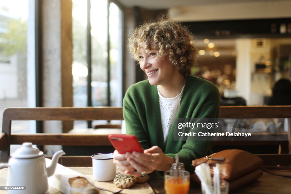 A 40 years old woman looking at her cell phone in a parisian cafe