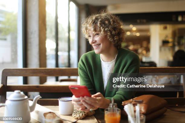 a 40 years old woman looking at her cell phone in a parisian cafe - 40 44 years 個照片及圖片檔