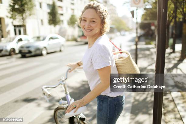 a 40 years old parisian woman with her bike in the streets of paris - shopping with bike stock-fotos und bilder