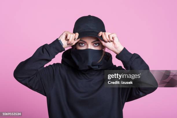 rebellische junge frau rosa hintergrund - protestor mask stock-fotos und bilder