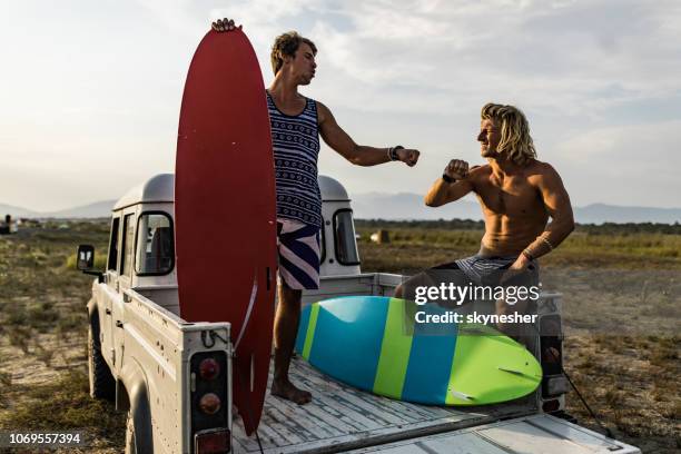 junge männliche surfer faust stoßen auf der rückseite des pick-up-truck. - welcome back stock-fotos und bilder