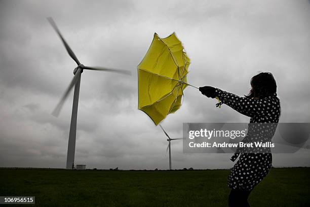 woman holding umbrella beneath wind turbines - wind fotografías e imágenes de stock