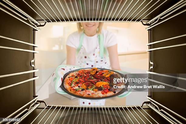 woman taking freshly baked pizza out of an oven - tray stock pictures, royalty-free photos & images