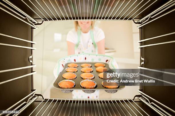 woman taking freshly baked buns out of an oven - backofen stock-fotos und bilder