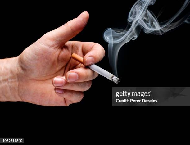 man's hand holding smoking cigarette - cigarette smoking stockfoto's en -beelden