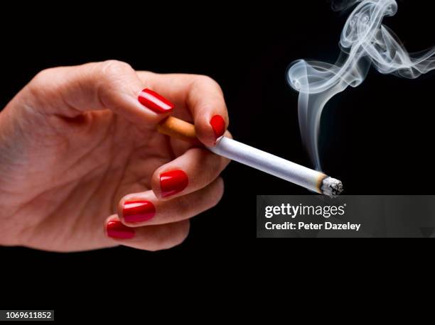 female hand holding smoking cigarette - smoking cigarette photos et images de collection