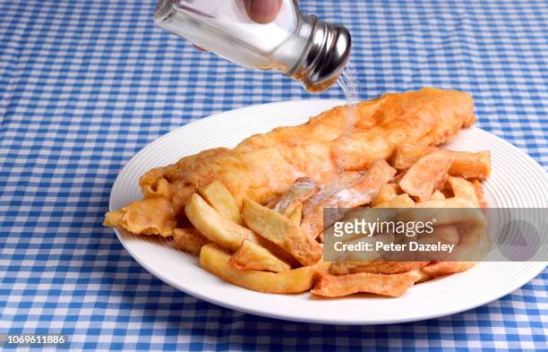pouring excess salt onto fish and chips - adicionar sal imagens e fotografias de stock