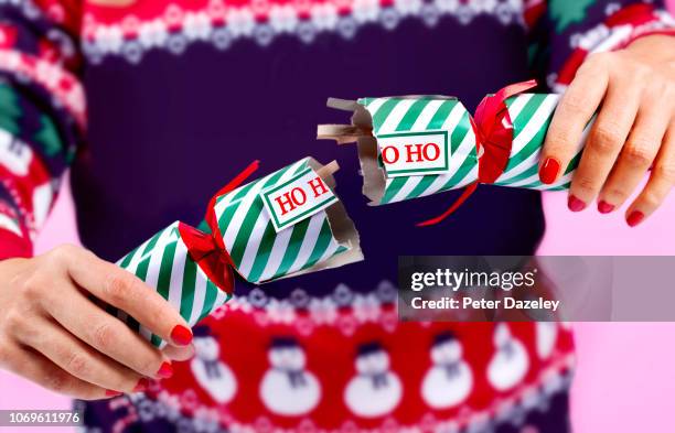woman alone at christmas, pulling a cracker with herself - christmas cracker stock pictures, royalty-free photos & images