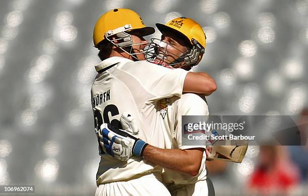 Michael Hussey of the Warriors is embraced by team mate Marcus North after reaching his century during day three of the Sheffield Shield match...