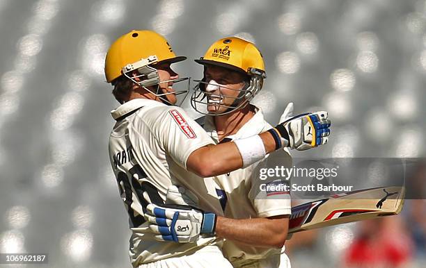 Michael Hussey of the Warriors is embraced by team mate Marcus North after reaching his century during day three of the Sheffield Shield match...