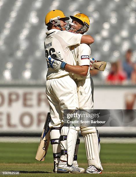Michael Hussey of the Warriors is embraced by team mate Marcus North after reaching his century during day three of the Sheffield Shield match...