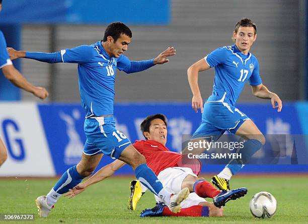 Kim Bo-Kyung of South Korea competes against Fozil Musaev and Ivan Nagaev of Uzbekistan during the men's quarter-final football match at the 16th...