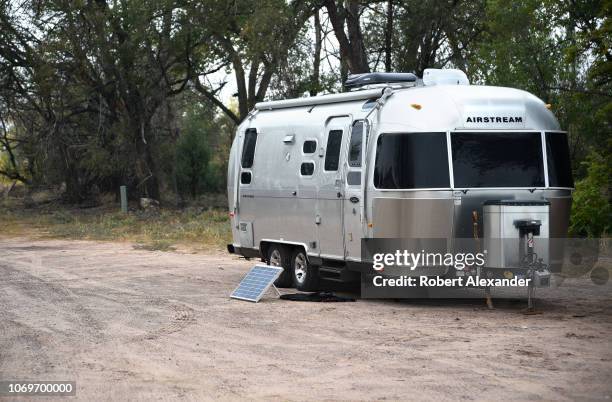 An Airstream travel trailer with a solar panel kit parked in Ojo Caliente, New Mexico.