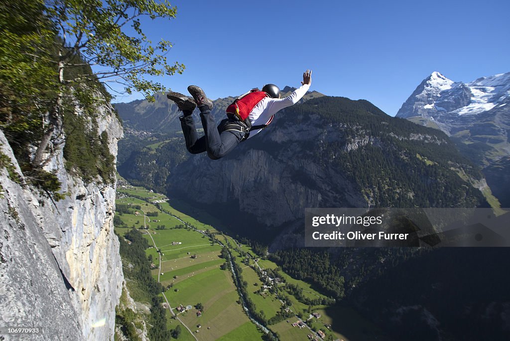 BASE jumper is diving into the valley from a cliff