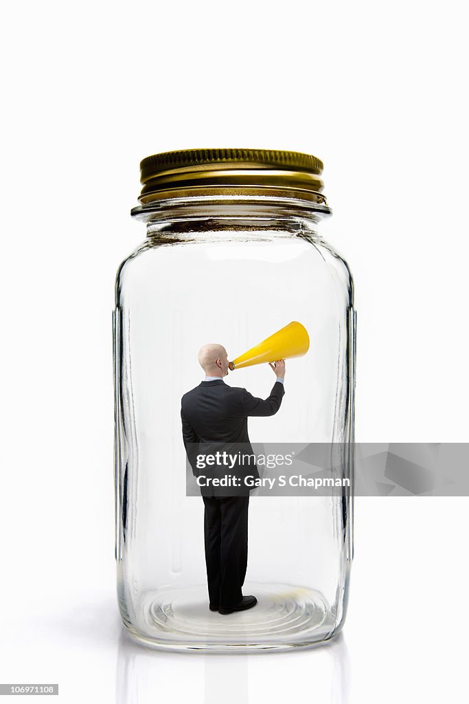 Businessman with megaphone inside mason jar.