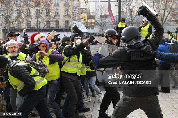 Riot police clash with men wearing "yellow vests" protestors on December 8, 2018 near the Arc de Triomphe in Paris during a protest against rising...