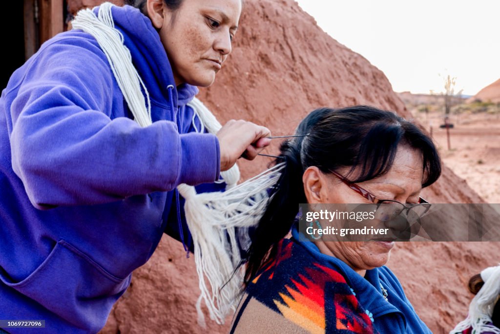 Native American Navajo Woman Styling another woman's hair in a traditional style