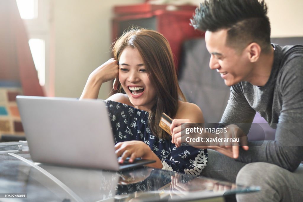 Happy couple shopping through laptop at home