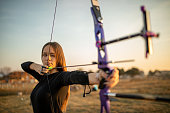 Teenage girl on archery training at sunset