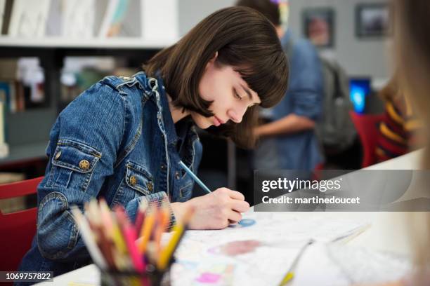étudiant jeune femme coloriages mandalas pour se détendre dans la bibliothèque de colege. - produit culturel photos et images de collection