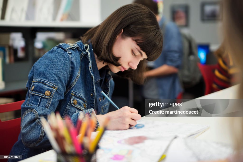 Young woman student coloring mandalas for relaxation in Colege library.