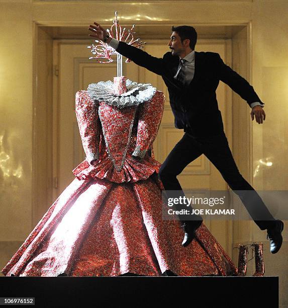 Sim Sim Wissgott Greek artist Nikos Floros jumps by his sculptural costume Queen Elisabeth II, utilizing aluminum cans, at the famous Austrian...
