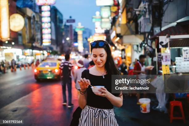 young woman eating shrimp tempura in bangkok chinatown district, thailand - street food stock pictures, royalty-free photos & images