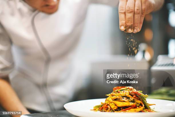 sprinkling seasonings from high up. - gourmet stock pictures, royalty-free photos & images