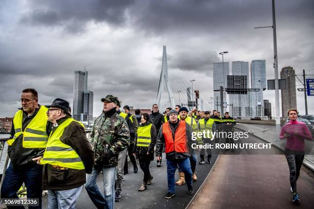 Woman jogs past protestors wearing "yellow vests" demonstrating on the Erasmusbrug in Rotterdam, The Netherlands, on December 8, 2018. - The...