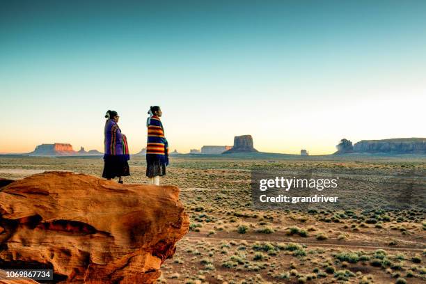 dos tradicionales navajo americanas nativo hermanas en monument valley tribal park en un rocky butte disfrutando de un amanecer o atardecer - indigenous culture fotografías e imágenes de stock