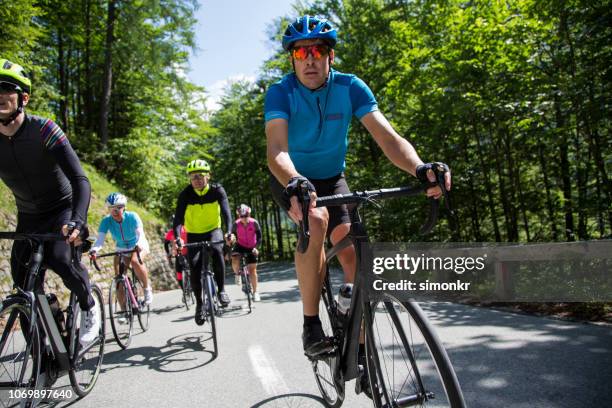 gruppe von rennradfahrer fahren rennräder auf bergstraße - straßenrennen stock-fotos und bilder