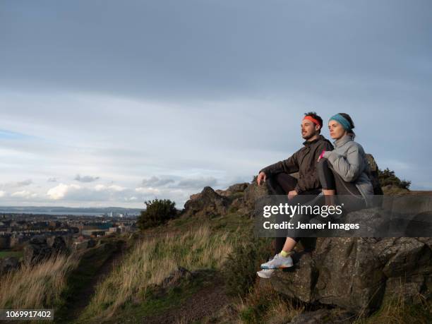 two people resting after hiking on a trail in the hills. - arthurs seat stock-fotos und bilder