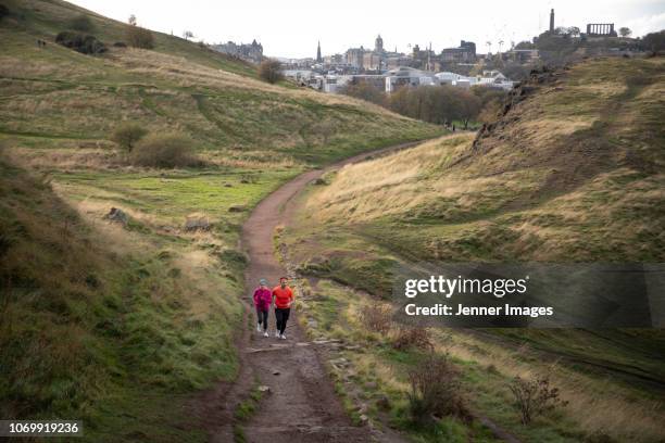 a couple out running on arthur's seat trail, edinburgh. - arthurs seat stock-fotos und bilder