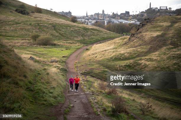 a couple out running on arthur's seat trail, edinburgh. - arthurs seat stock pictures, royalty-free photos & images