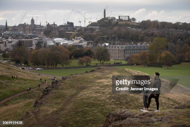 a couple enjoying the view of edinburgh from arthur's seat. - arthurs seat stock pictures, royalty-free photos & images