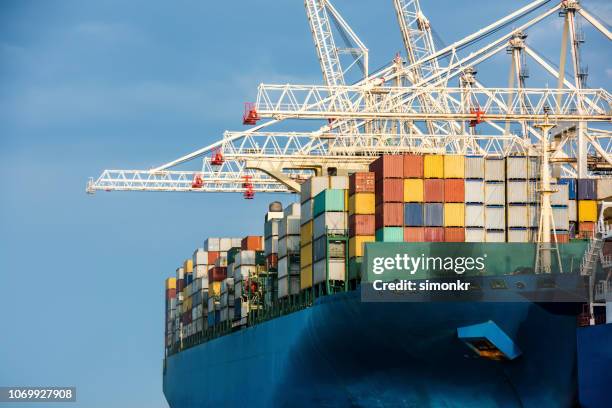 cargo ship moored while being loaded with containers - container ship stock pictures, royalty-free photos & images