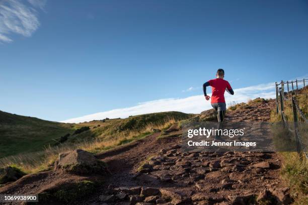 athletic man trail running up a mountainside. - midlothian scotland stock pictures, royalty-free photos & images
