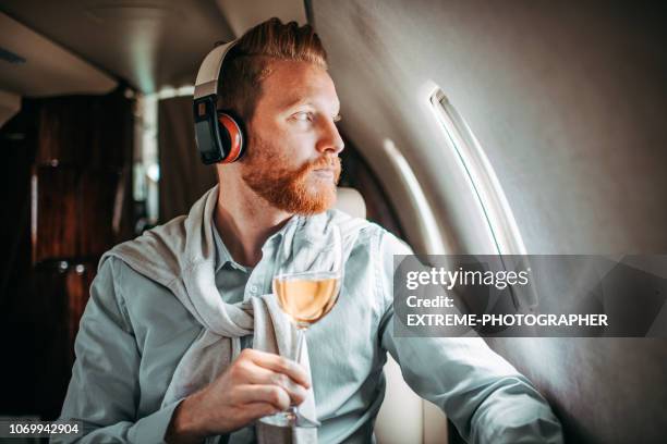 young businessman drinking wine on a private jet - first class flight stock pictures, royalty-free photos & images