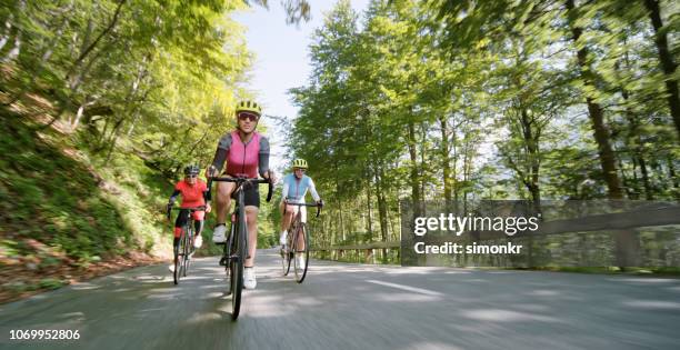 three women riding road bikes on mountain road - road cycling stock pictures, royalty-free photos & images