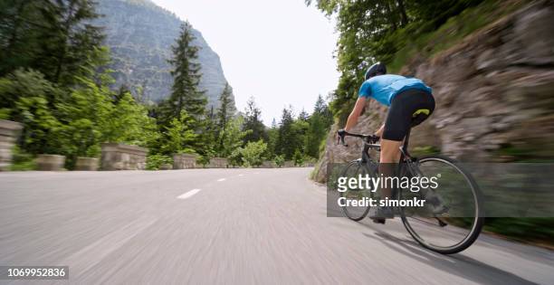 mann reiten rennrad auf bergstraße - sports round stock-fotos und bilder