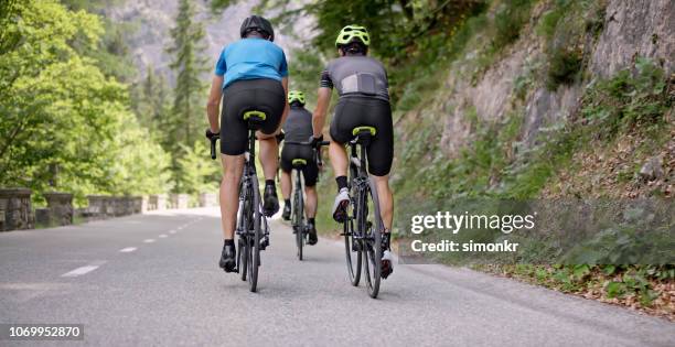 drie mannen rijden racefietsen op bergweg - wielrennen stockfoto's en -beelden