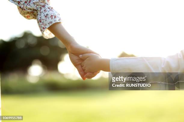 mother walking hand in hand with daughter - 背中 手 ストックフォトと画像